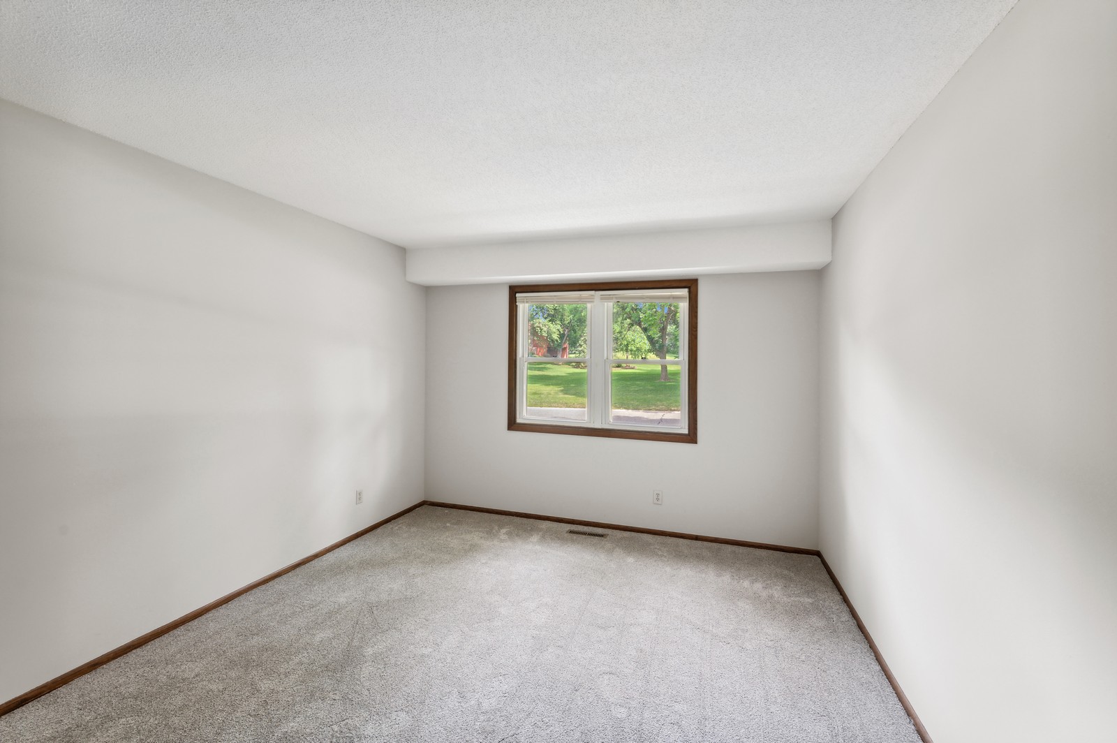 Spacious bedroom at Blossom Hill Assisted Living in Woodbury, MN, with a large bed, nightstand, and plenty of natural light